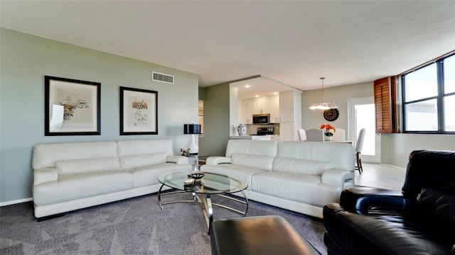 living area with a chandelier, carpet, visible vents, and baseboards