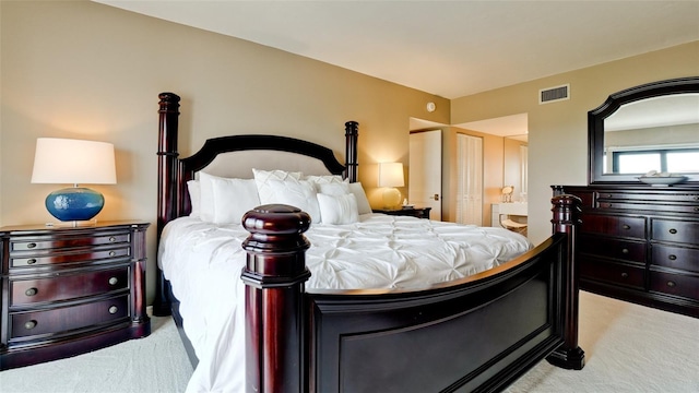 bedroom featuring light colored carpet, visible vents, and ensuite bath