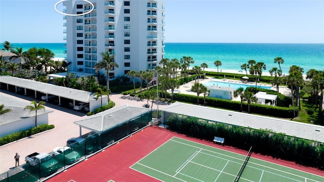 view of tennis court featuring a water view and a community pool