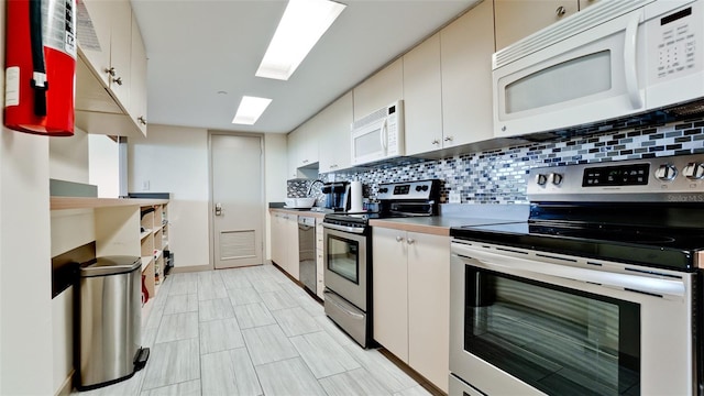 kitchen featuring stainless steel appliances, decorative backsplash, light tile patterned floors, and white cabinets