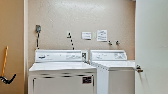 laundry area with a textured wall and washer and clothes dryer