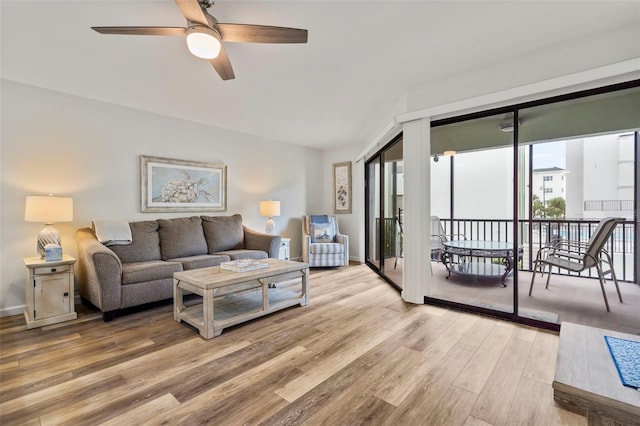 living room with light wood-style floors, ceiling fan, and baseboards