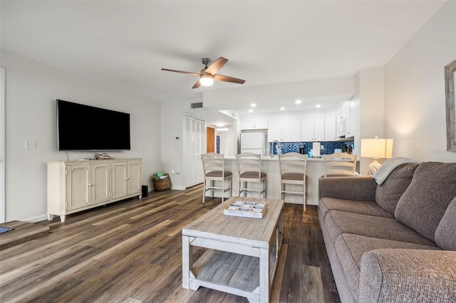 living room featuring a ceiling fan, baseboards, visible vents, and dark wood-type flooring