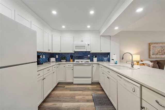 kitchen featuring light countertops, white cabinetry, a sink, white appliances, and a peninsula