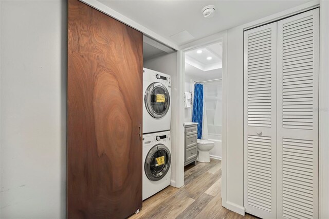 clothes washing area with stacked washer and clothes dryer and hardwood / wood-style flooring