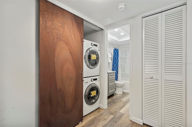 laundry area with stacked washing maching and dryer, light wood-style flooring, laundry area, and recessed lighting