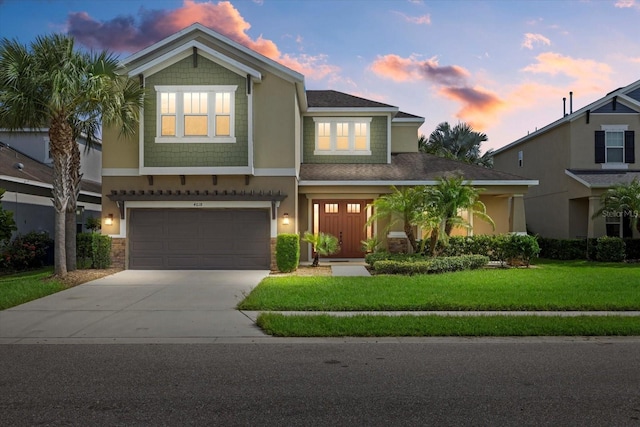 view of front of home with concrete driveway, an attached garage, a front lawn, and stucco siding