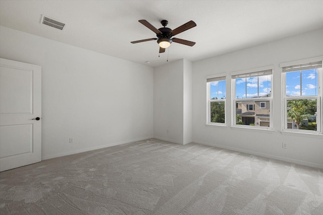 empty room with ceiling fan, light colored carpet, and plenty of natural light