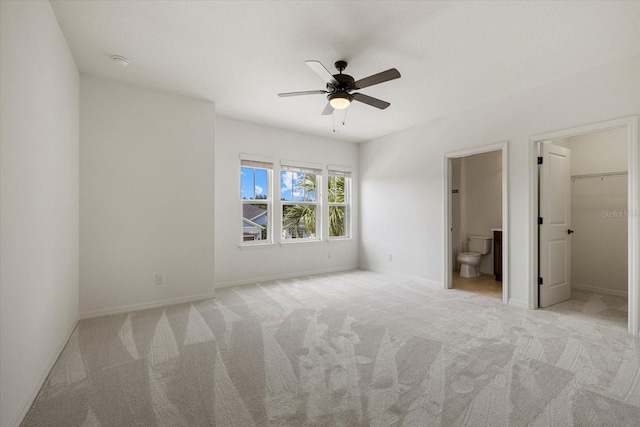 unfurnished bedroom featuring ceiling fan, light carpet, and a walk in closet