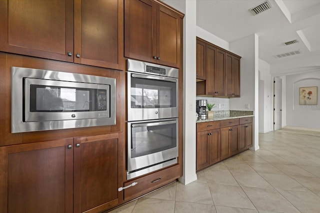 kitchen with light tile patterned flooring, light stone countertops, and appliances with stainless steel finishes