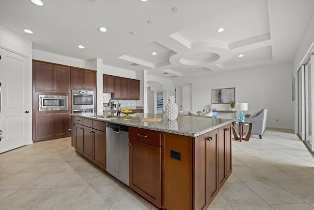 kitchen featuring sink, light stone counters, appliances with stainless steel finishes, an island with sink, and coffered ceiling