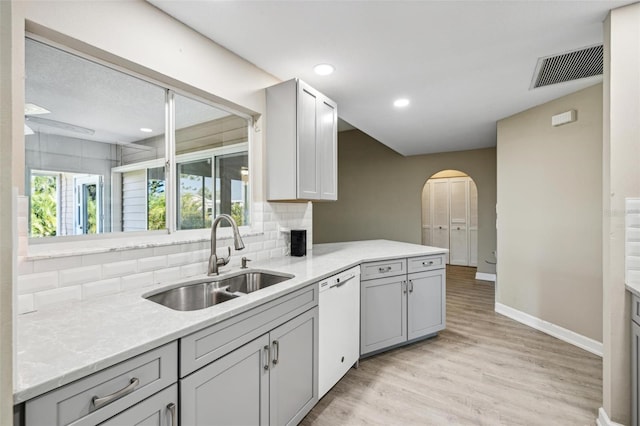 kitchen featuring dishwasher, light hardwood / wood-style floors, decorative backsplash, sink, and gray cabinets