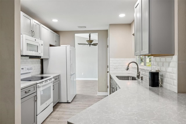 kitchen featuring ceiling fan, light hardwood / wood-style flooring, backsplash, sink, and white appliances