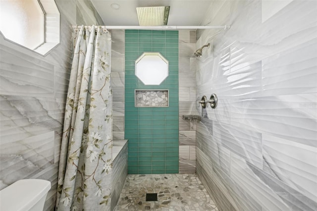 bathroom with tile walls, a shower with curtain, and toilet