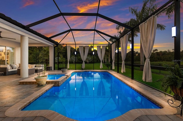 pool at dusk with an outdoor living space, an in ground hot tub, a patio area, and glass enclosure