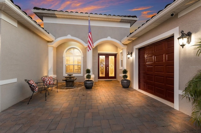 exterior entry at dusk with french doors and a garage