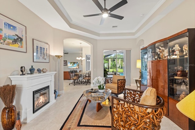 sitting room with ceiling fan with notable chandelier, a tray ceiling, light tile patterned floors, and ornamental molding