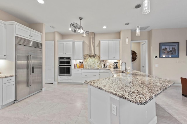 kitchen featuring pendant lighting, sink, white cabinets, wall chimney range hood, and stainless steel appliances