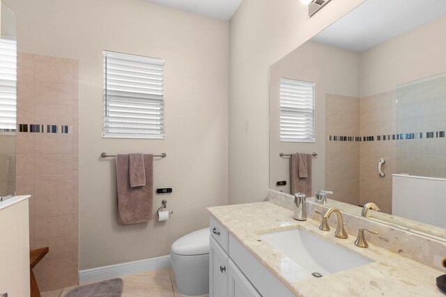 bathroom with tiled shower, vanity, toilet, and tile patterned floors