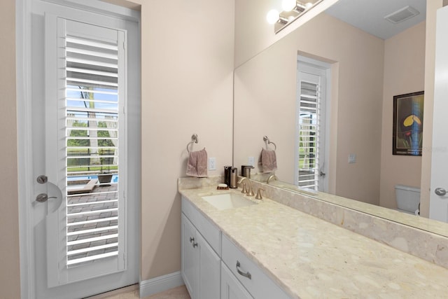 bathroom featuring toilet, baseboards, visible vents, and vanity