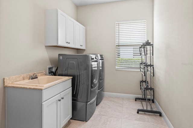 washroom featuring cabinet space, a sink, washer and clothes dryer, and baseboards