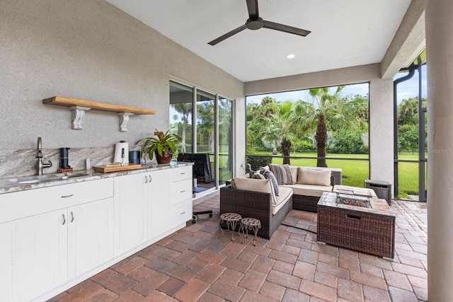 sunroom / solarium featuring ceiling fan, sink, and a healthy amount of sunlight