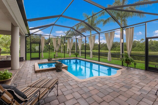 view of swimming pool featuring glass enclosure, an in ground hot tub, and a patio area