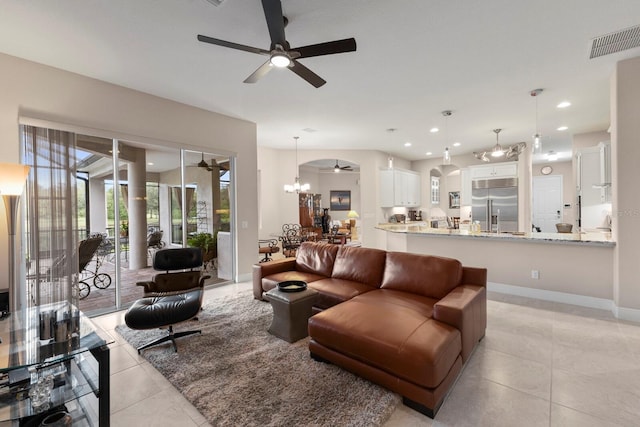 living room with ceiling fan with notable chandelier and light tile patterned floors