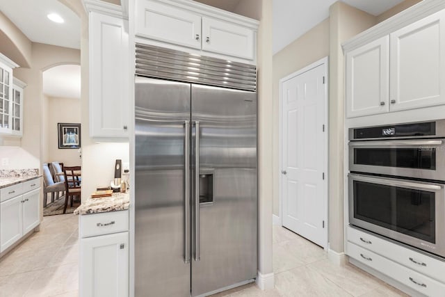 kitchen with appliances with stainless steel finishes, glass insert cabinets, and white cabinets