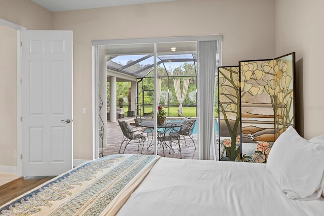 bedroom with a sunroom, baseboards, access to exterior, and wood finished floors