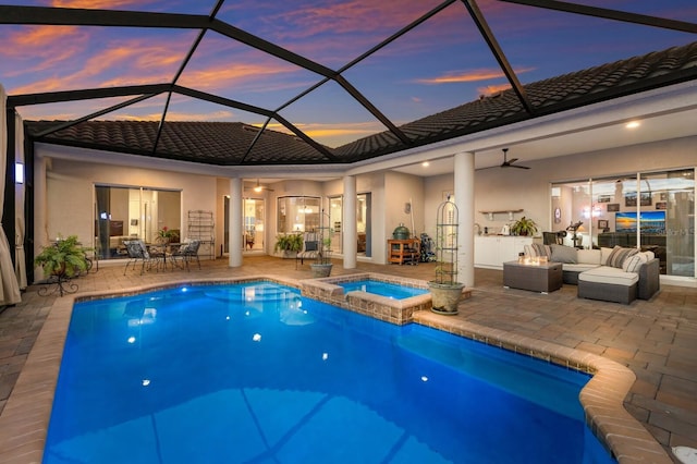 view of swimming pool with ceiling fan, glass enclosure, outdoor lounge area, a pool with connected hot tub, and a patio area