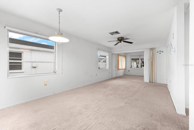 unfurnished living room with carpet floors, a healthy amount of sunlight, ceiling fan, and visible vents