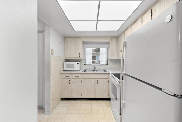 kitchen featuring white appliances, light countertops, and a sink