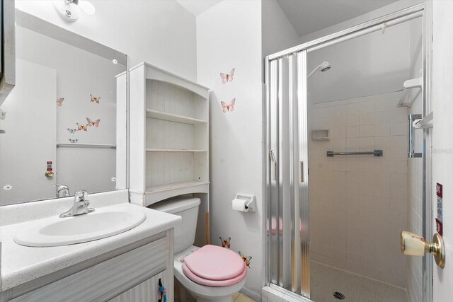 bathroom featuring a shower with door, toilet, and vanity