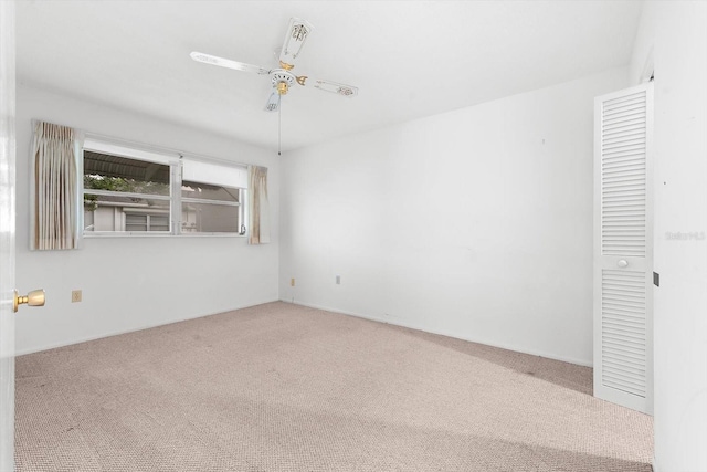 carpeted spare room featuring ceiling fan