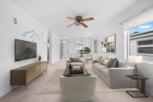 living room featuring a ceiling fan, a healthy amount of sunlight, and light carpet