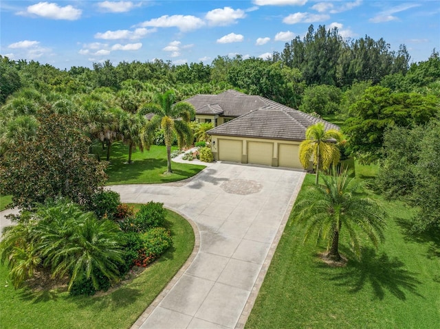 view of front of property with a front yard, a tiled roof, an attached garage, and driveway