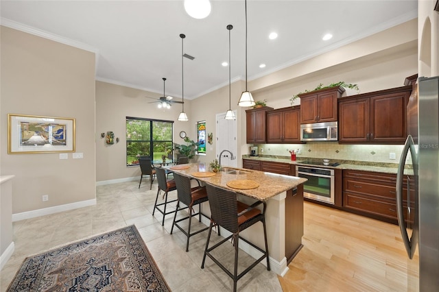 kitchen with backsplash, crown molding, a breakfast bar area, stainless steel appliances, and a sink