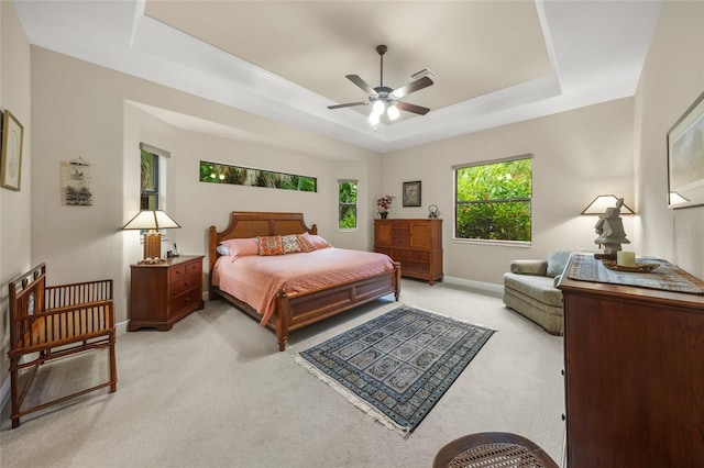 bedroom with baseboards, a raised ceiling, light colored carpet, and a ceiling fan