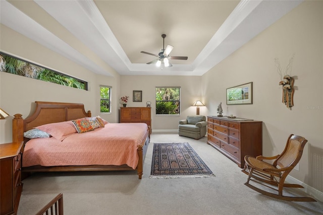 bedroom with a ceiling fan, a raised ceiling, light colored carpet, and baseboards