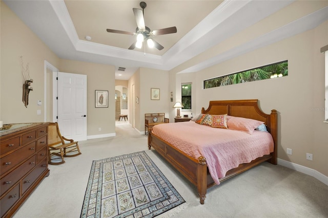 bedroom featuring a tray ceiling, arched walkways, light colored carpet, and baseboards