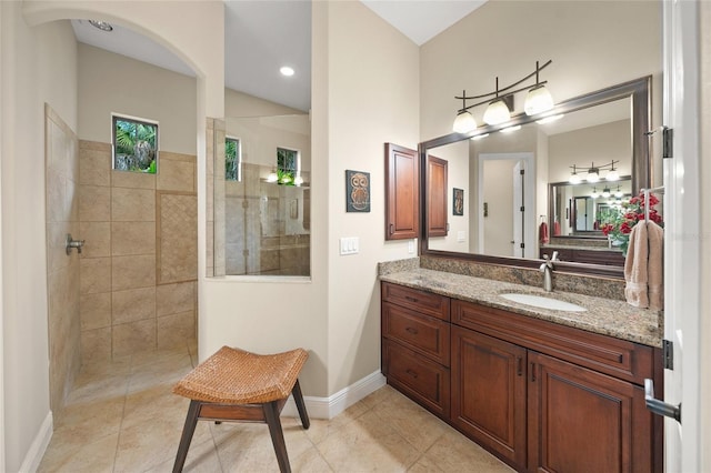 full bathroom featuring tile patterned floors, baseboards, vanity, and a walk in shower