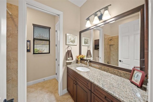 bathroom featuring vanity, tile patterned floors, baseboards, and tiled shower