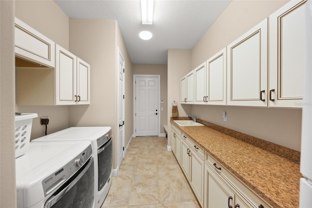 laundry room featuring baseboards, cabinet space, a sink, a textured ceiling, and washer and dryer