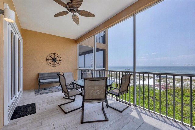 sunroom / solarium featuring a view of the beach, ceiling fan, and a water view