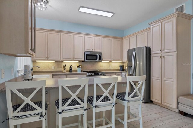 kitchen with a kitchen bar, decorative backsplash, sink, and appliances with stainless steel finishes