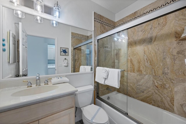 full bathroom with washer / dryer, vanity, combined bath / shower with glass door, and toilet