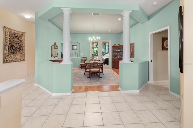 dining room featuring ornate columns, ornamental molding, an inviting chandelier, and light wood-type flooring