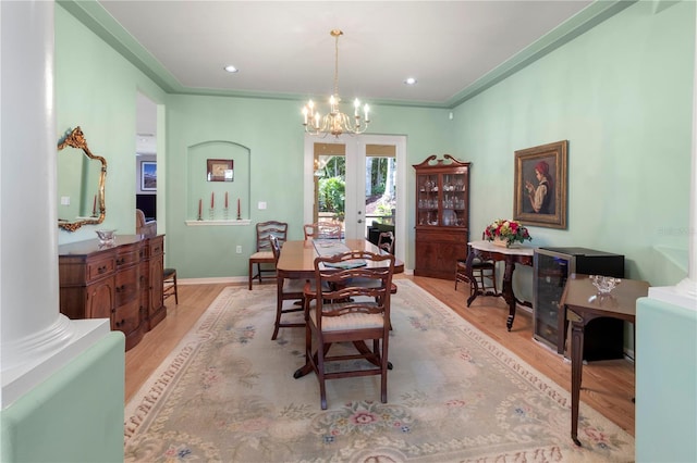 dining area with ornamental molding, decorative columns, a chandelier, and light hardwood / wood-style flooring