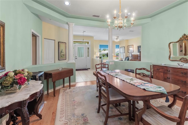 dining space featuring ornate columns, a chandelier, and light wood-type flooring